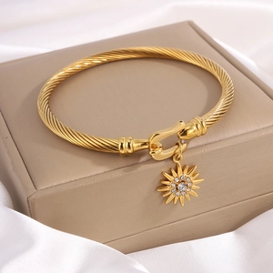 Golden titanium steel twisted cable bangle with sun pendant and shimmering crystals