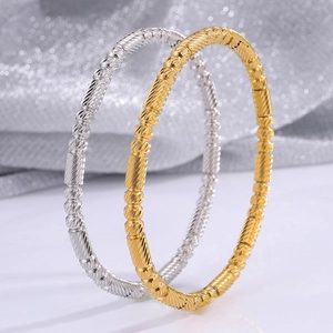 Macro shot of gold and silver bamboo bead bracelets with spiral textures on a silk background