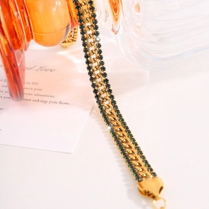 Macro shot of 18k gold plated stainless steel chain with green rhinestones and vintage texture