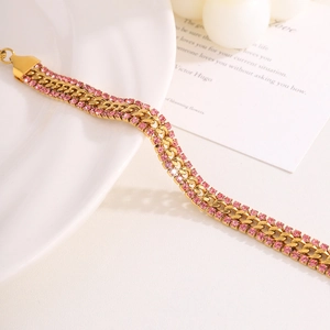Detail of gold-plated Cuban link bracelet with two rows of pink rhinestones on a white plate