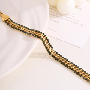 Detail view of double-layered gold bracelet with dark green zircon stones and polished clasp