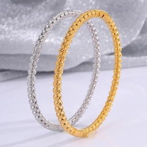 Close-up of gold and silver stainless steel bangles with spiral beaded texture details