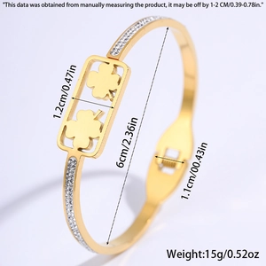 Detailweergave van de gouden titanium stalen C-armband met klaver en kristallen