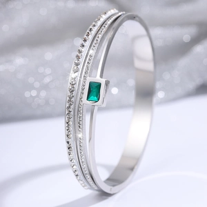 Macro shot of silver-tone triple-layer steel bracelet with crystals and emerald gemstone