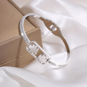 Detail van een zilveren klaverarmband met ingelegde diamanten op zijde