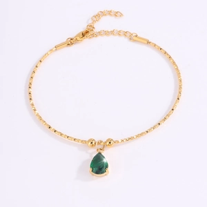 Detalle de pulsera de cadena dorada con gema verde talla pera y cierre de mosquetón