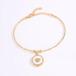 Detalle de una pulsera dorada con dije de abeja en esmalte blanco y cierre de mosquetón