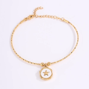 Detalle de pulsera dorada con colgante de estrella esmaltada y cierre de mosquetón