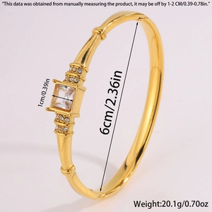Detail of gold open bangle featuring a large square zircon and double rows of side stones