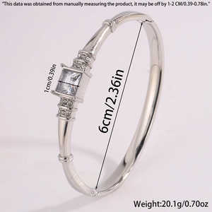 Detailed macro view of silver steel bangle with a square central zircon and paved side stones