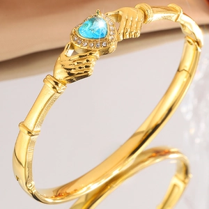Macro shot of gold Claddagh bracelet with heart blue gemstone and crystal accents