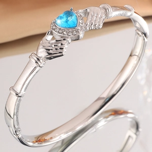 Macro detail of silver Claddagh cuff bracelet with blue heart stone and zircon pave