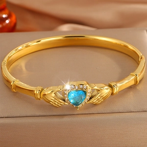 Detail of Claddagh gold bangle featuring blue heart gemstone and sparkling crystal halo