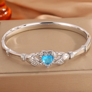 Detail of silver Claddagh bracelet with blue heart stone on golden jewelry box
