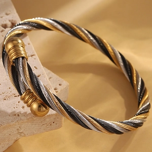 Détail macro du bracelet manchette à câbles torsadés tricolores or, argent et noirs