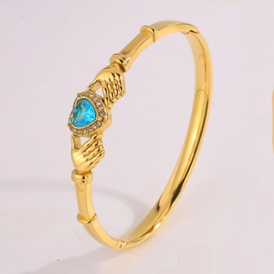 Macro shot of gold Claddagh bracelet featuring heart-shaped blue gem and zircon inlay