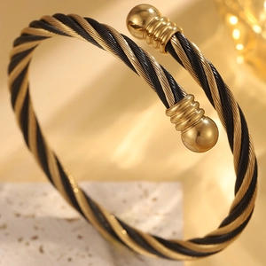 Détail macro d'un bracelet câble torsadé bicolore or et noir avec embouts sphériques