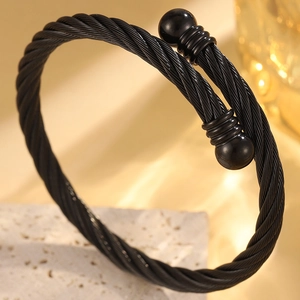 Détail du bracelet câble noir torsadé avec embouts sphériques et texture acier robuste