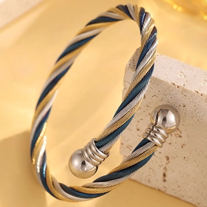 Vue macro du bracelet jonc torsadé tricolore en acier inoxydable sur une pierre