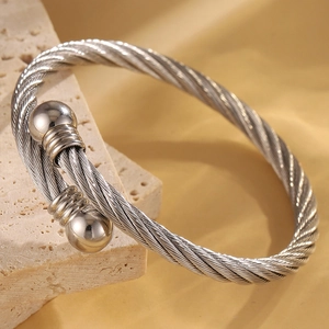 Vue macro d'un bracelet jonc en fil d'acier torsadé argenté avec embouts à billes