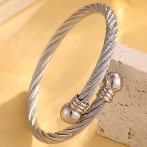 Vue macro d'un bracelet câble en acier titane argenté avec boules polies sur pierre
