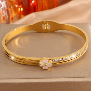 Détail du bracelet trèfle doré avec zircons sertis et motifs de cœurs évidés