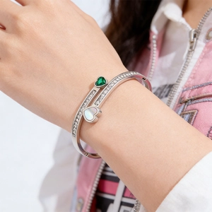 Close-up of titanium steel bracelet with green emerald heart zircon and silver finish