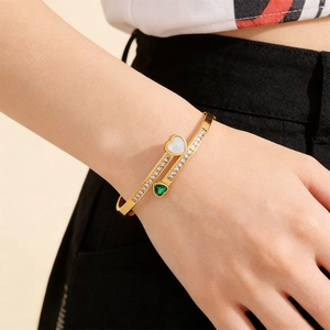 Close-up of a double-layered gold bracelet featuring emerald hearts and cubic zirconia