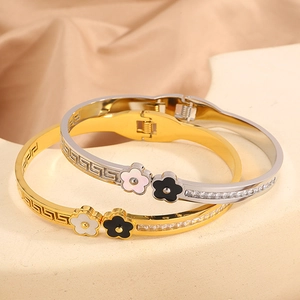 Detail of gold and silver clover bangles with meander pattern and pave crystals