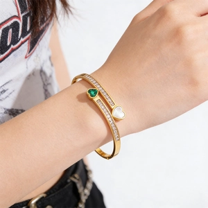 Gold plated stainless steel bracelet featuring green emerald heart and white shell inlay
