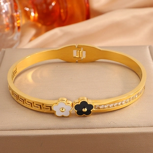 Detail of gold-plated bangle featuring black and white flowers with Greek key patterns
