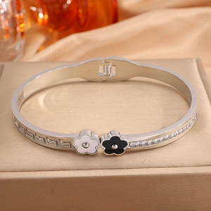 Macro shot of silver titanium steel clover bangle with Greek fret pattern and zircons