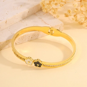 Macro detail of gold clover bracelet with Greek key pattern and cubic zirconia