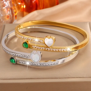 Detailed macro view of heart emerald zircon bangles on silk and velvet jewelry box