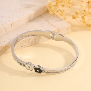 Detailed macro of silver steel bracelet featuring double floral charms and diamond accents