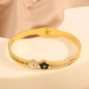 Macro detail of gold-plated stainless steel bangle with enamel flowers and Greek fret pattern