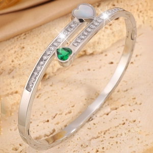 Macro shot of silver titanium bypass bracelet with emerald heart and white stones