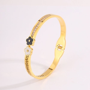 Detail view of gold clover bangle with black and white petals and geometric pattern