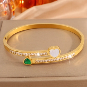 Detailed macro of 18K gold plated heart bracelet with emerald zircon and silk background
