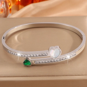 Macro shot of silver titanium steel bangle with emerald heart gemstone and pavé zircon stones
