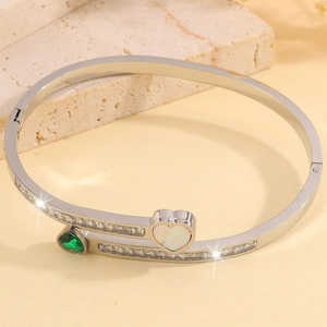 Detail of silver heart bangle with emerald stone, mother of pearl and paved diamonds