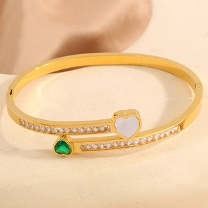 Macro shot of gold stainless steel bangle with emerald heart and double row zircons