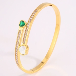 Detail of gold titanium steel bracelet with green heart stone and white shell heart charm