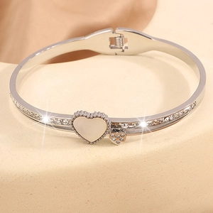 Détail macro du bracelet en acier avec cœur en nacre et pavage de zircons étincelants