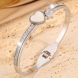 Vue macro d'un bracelet cœur en argent avec nacre et cristaux sur un socle de grès