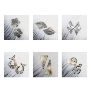 Detailed view of six natural black shell pendants with tribal and floral carvings