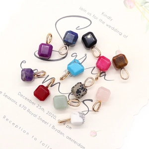 Multiple square natural stone pendants with gold clasps on a floral invitation card