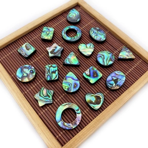 Natural abalone shell beads in star, heart, and teardrop shapes on a bamboo tray