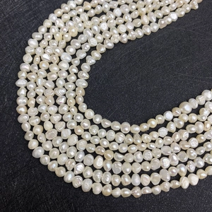Macro shot of irregular white freshwater pearls showing natural luster on a dark background