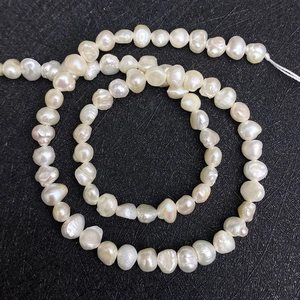 Detailed view of natural white baroque freshwater pearls with iridescent luster on black background